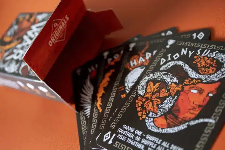 Cards At War: The Battle For Ancient Greece Photo #0866 Four god cards from Cards At War fanned out in front of an open card box.