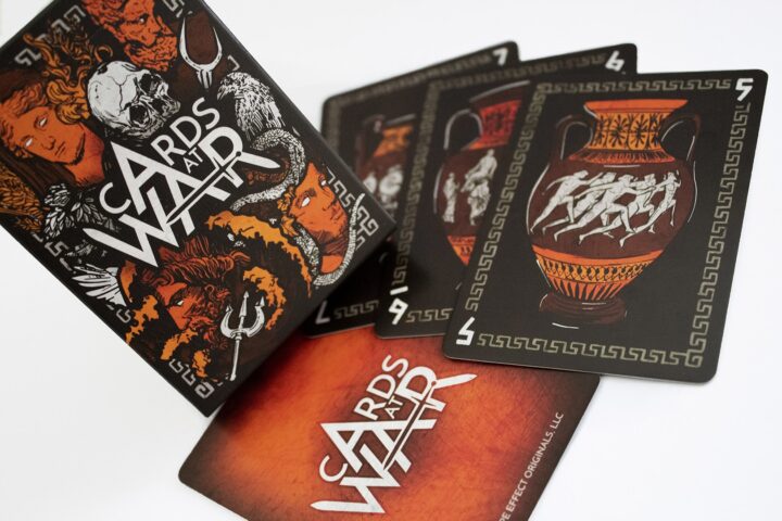 Cards At War: The Battle For Ancient Greece Photo #1274 Four cards from Cards At War are arranged on a table with a card box on top of them.