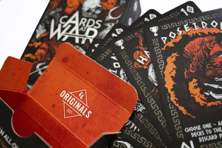 Cards At War: The Battle For Ancient Greece Photo #1313 Four cards from Cards At War are resting on top of a card box, with an open box in front of them.