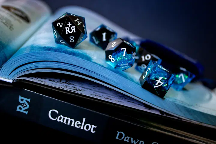 Glistening In The Light An iridescent set of dice placed upon an adventure roleplaying book.