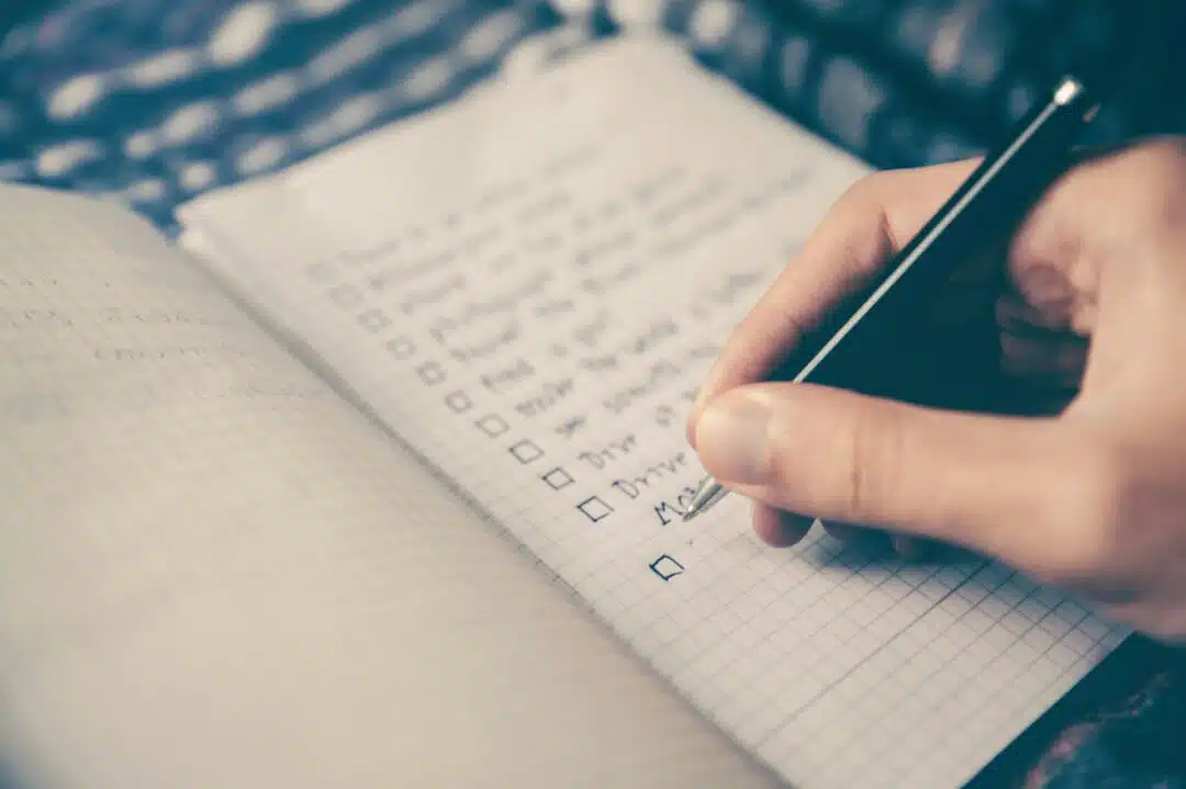 A notebook open with a checklist being written inside on a page.