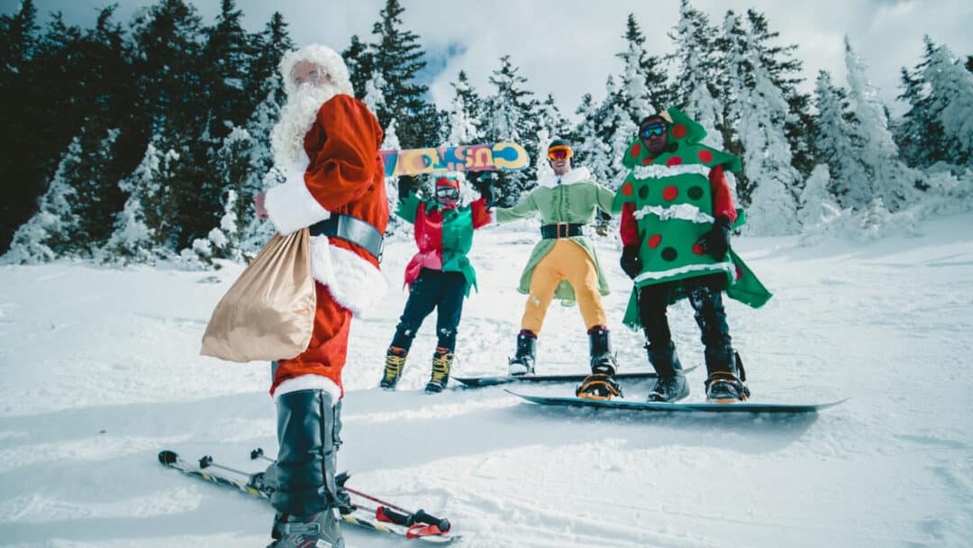 A group of people wearing Christmas-themed costumes while playing in the snow.