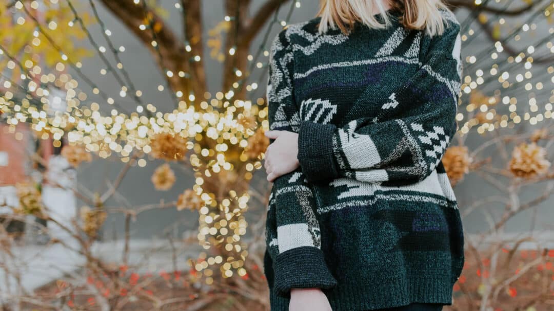 A woman wearing a Christmas sweater. You can wear a fun sweater to a Christmas escape room.