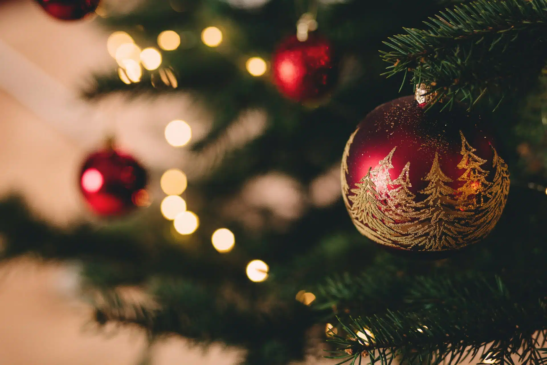 Red ornaments adorn a Christmas tree.