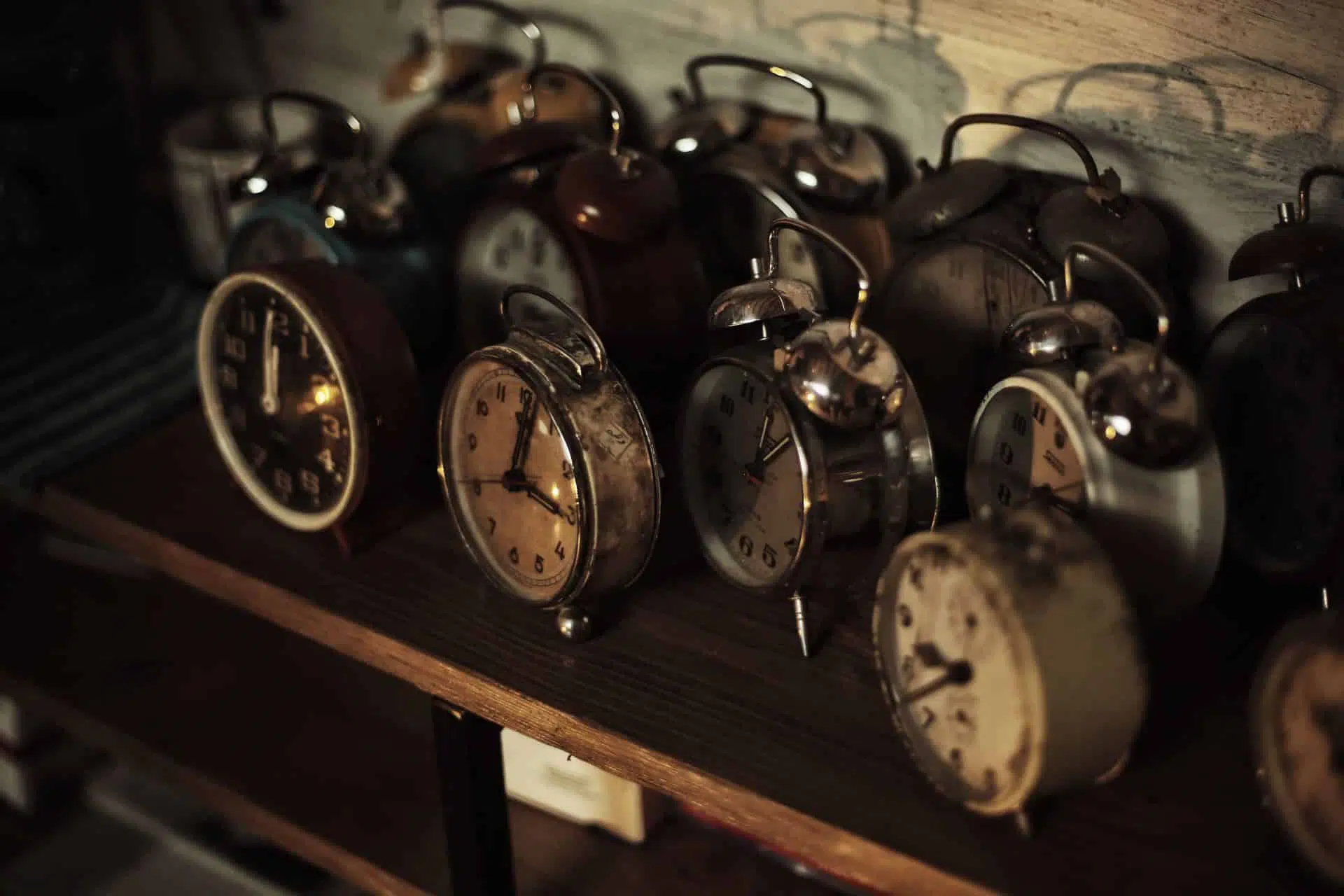 A collection of old-school alarm clocks sitting on a shelf. Losing track of time is a common escape room beginner mistake.