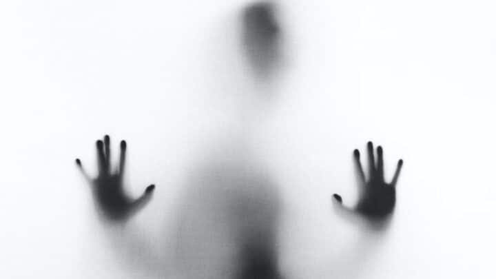 A creepy shadow pressing its hands against glass.