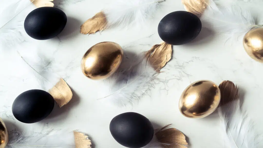 Gold and black Easter eggs on a marble table.