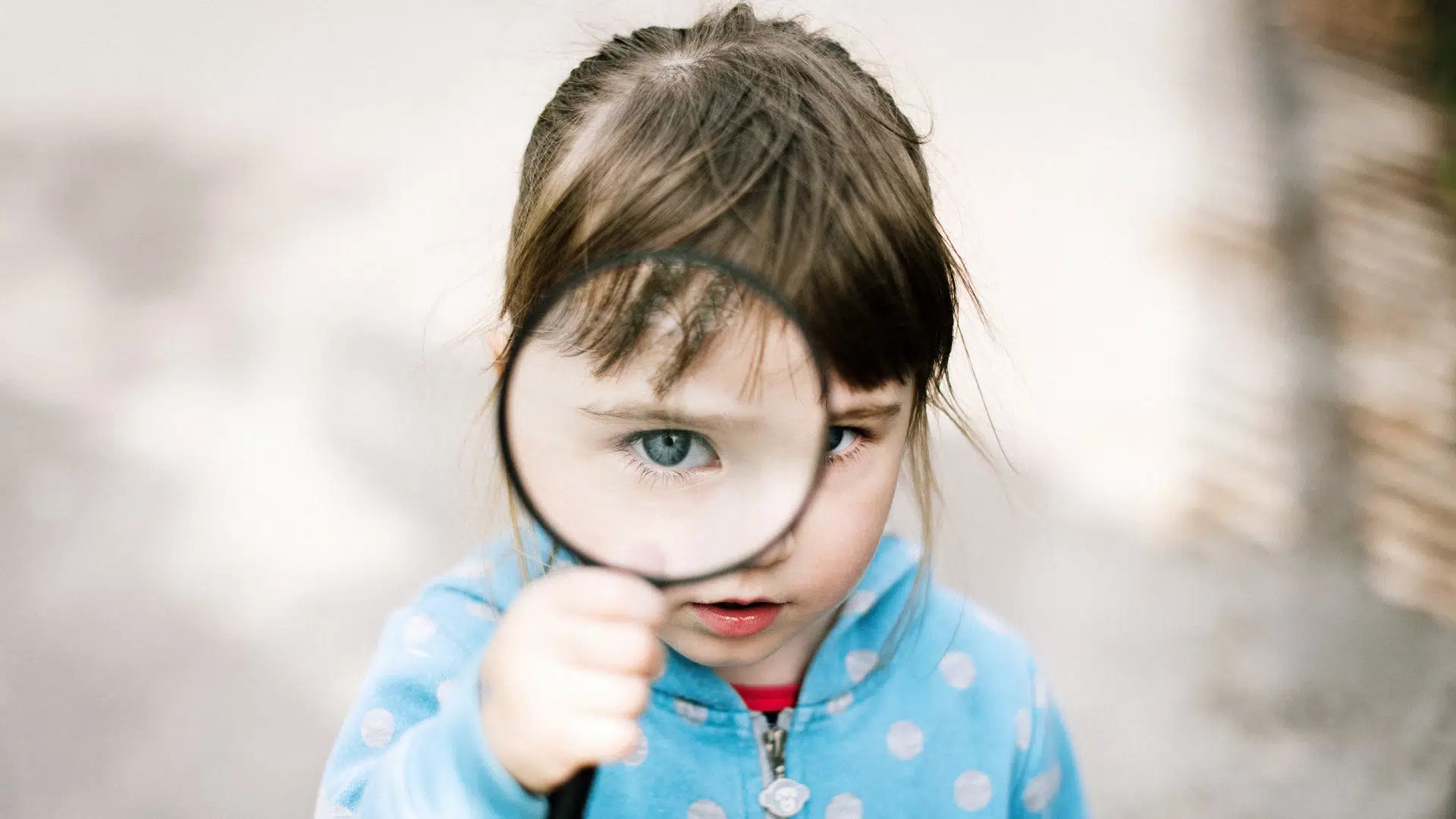 A photo of a girl looking through a magnifying glass.