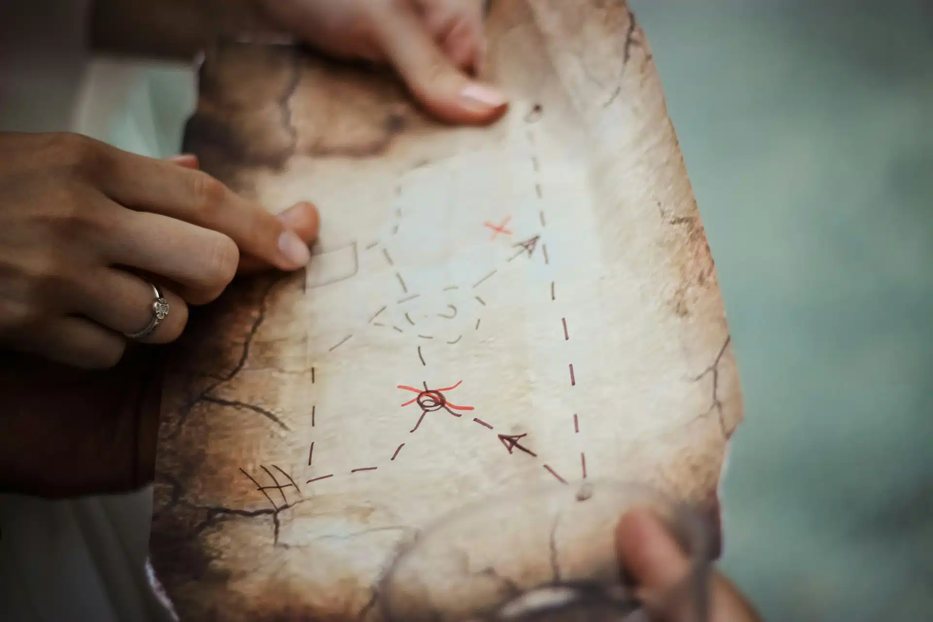 Hands hold a distressed map, leading to potential treasure.