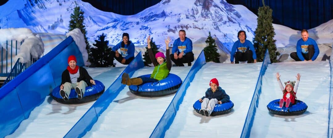 A family sits in innertubes and slide down a snowy mountain.
