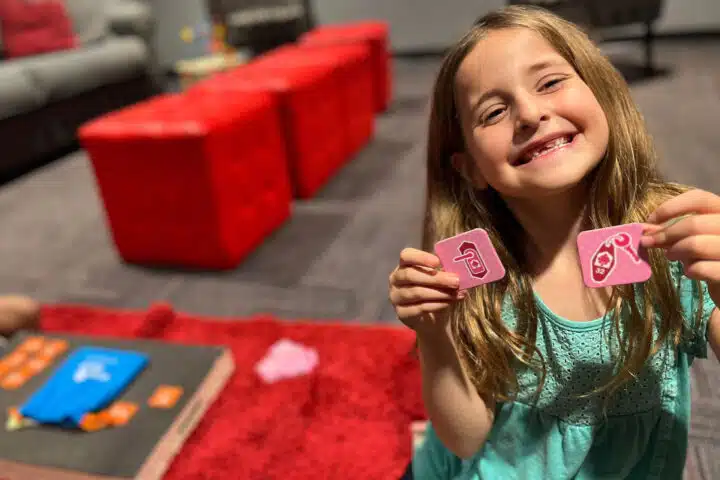 A child holding two matching Pick Up Locks tiles.