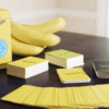 A medium-shot photo of Fanatics Gone Bananas, including the rotten box, decks of cards, cards fanned out, and a bunch of bananas on a table.
