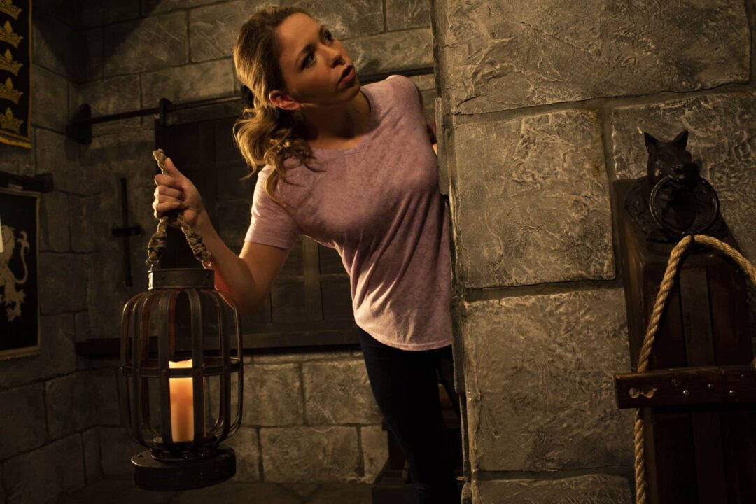 Player holding a lantern and looking around the castle corner.