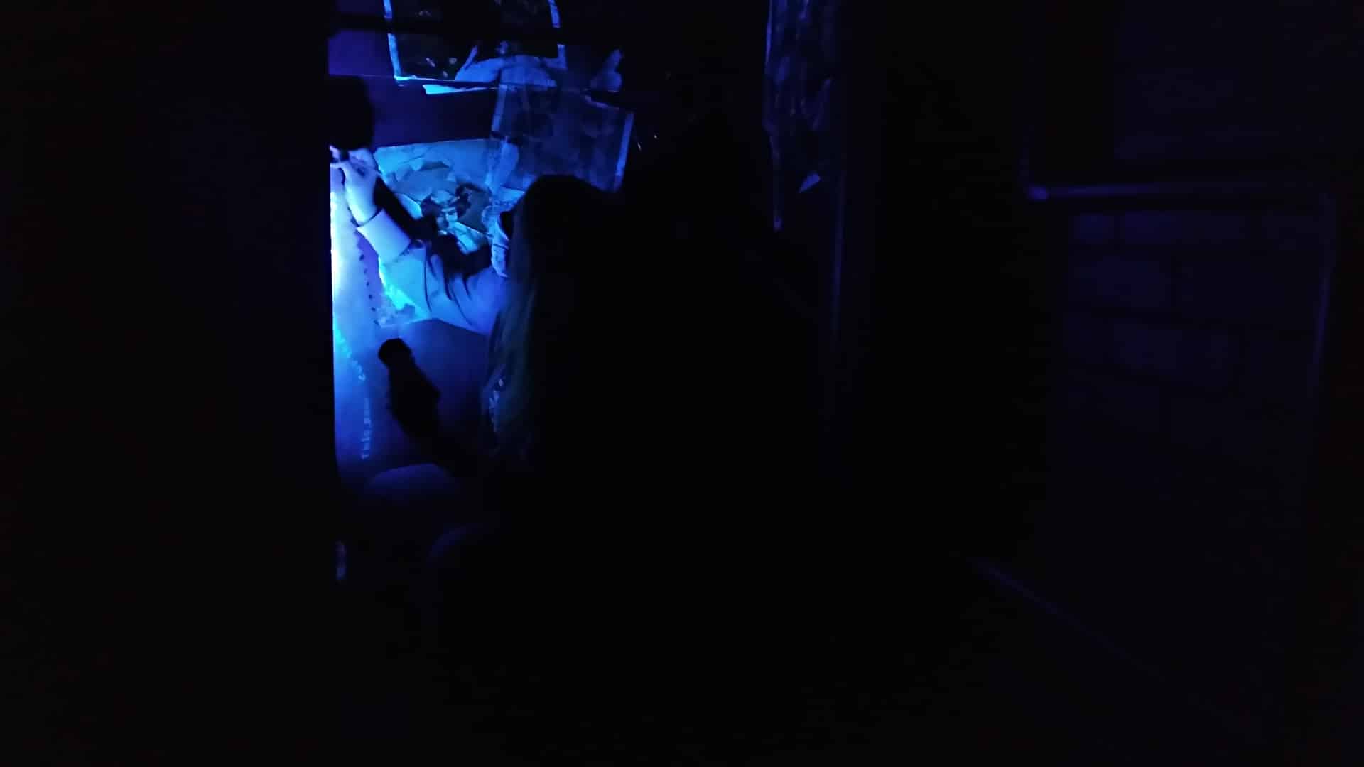 One of the escape room maintenance team members painting a clue by blacklight.