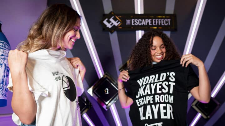 Two players hold up escape room themed tees.