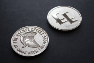 Two coins depicting a Spartan helmet and The Escape Effect logo.