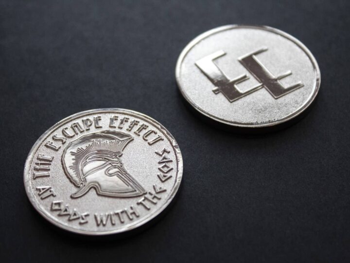 Two coins depicting a Spartan helmet and The Escape Effect logo.