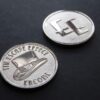 Two coins depicting a top hat and The Escape Effect logo