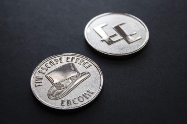 Two coins depicting a top hat and The Escape Effect logo