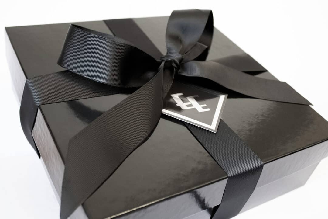 A black gift box with a ribbon around it.