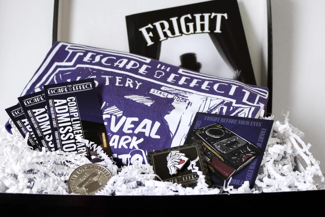 A gift box including tickets, sticker, pin, coin, shirt and comic.