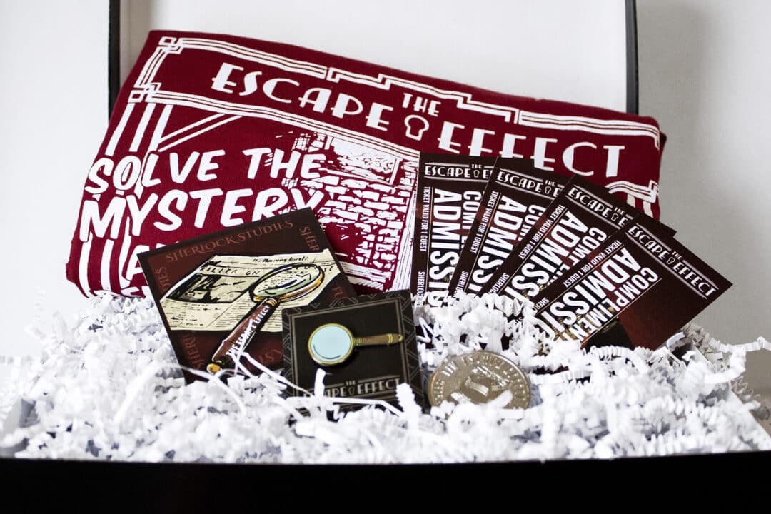 A gift box including tickets, sticker, pin, coin, and shirt.