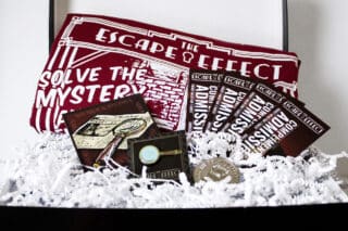 A gift box including tickets, sticker, pin, coin, and shirt.
