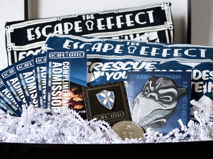 A gift box including tickets, sticker, pin, coin and shirts.