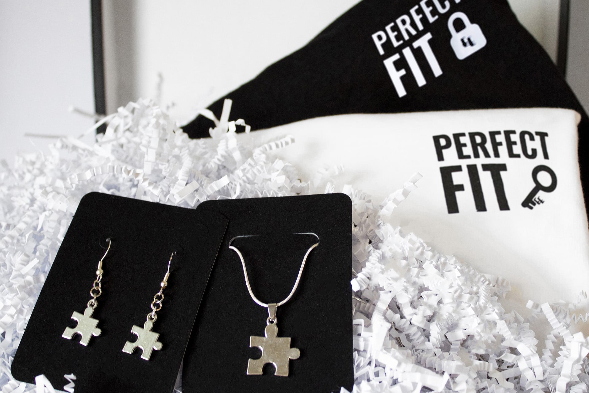 A gift box comprising of two shirts and puzzle piece jewelry.