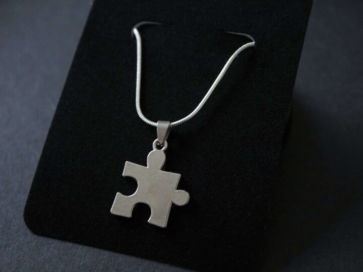 A photograph of a necklace with a puzzle piece pendant charm.