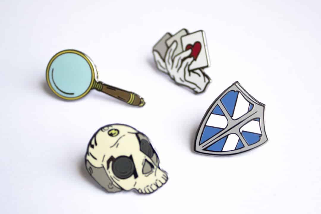 The four pins available as badges for the Pokemon Go event: a magnifying glass, a shield, a skull, and a hand holding playing cards.