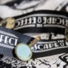 A "The Escape Effect" lanyard with skull, compass, and magnifying glass lapel pins.