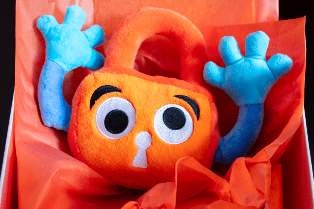 Paddy Padlock bursts out of a box, surrounded by orange tissue paper.