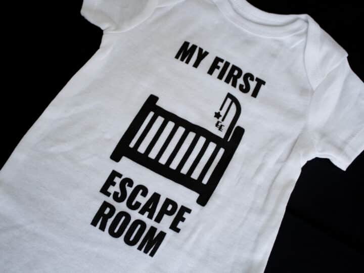 A photo showing a baby onesie with the phrase My First Escape Room.