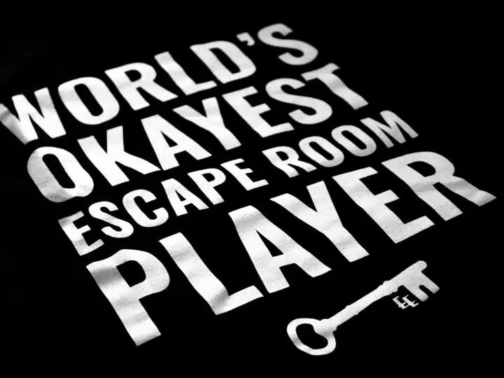 A photo showing a shirt with the phrase World's Okayest Escape Room Player.