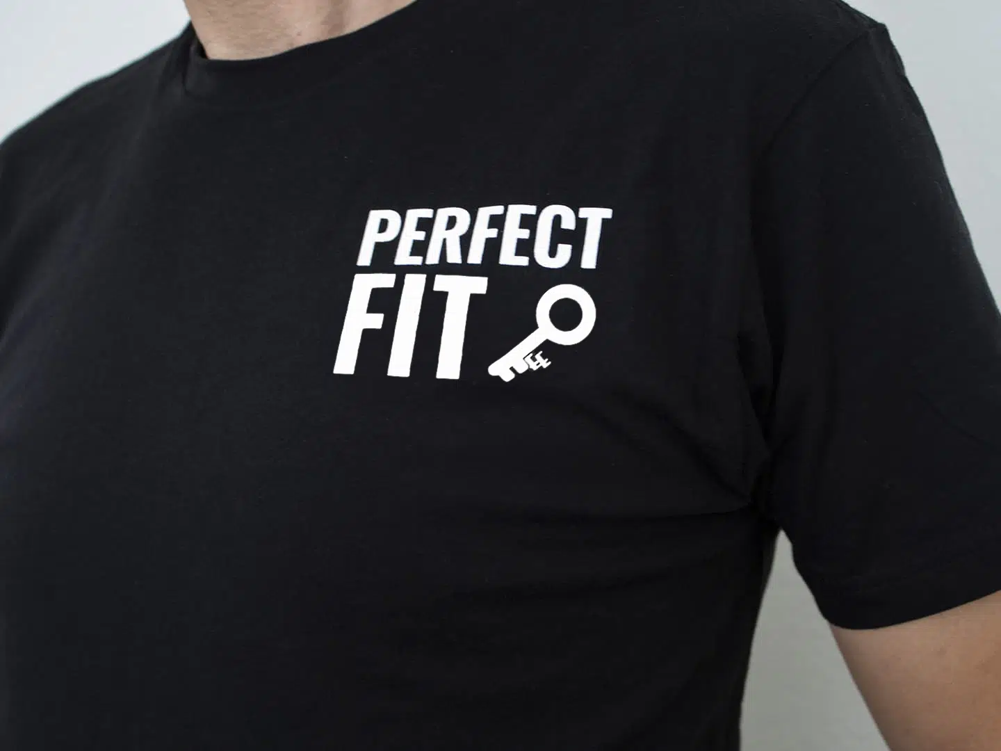 A photo showing a shirt with the phrase Perfect Fit, with an image of a key.