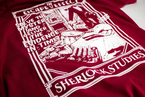 A red "Sherlock Studies" shirt featuring an illustration of detectives inspecting a study.