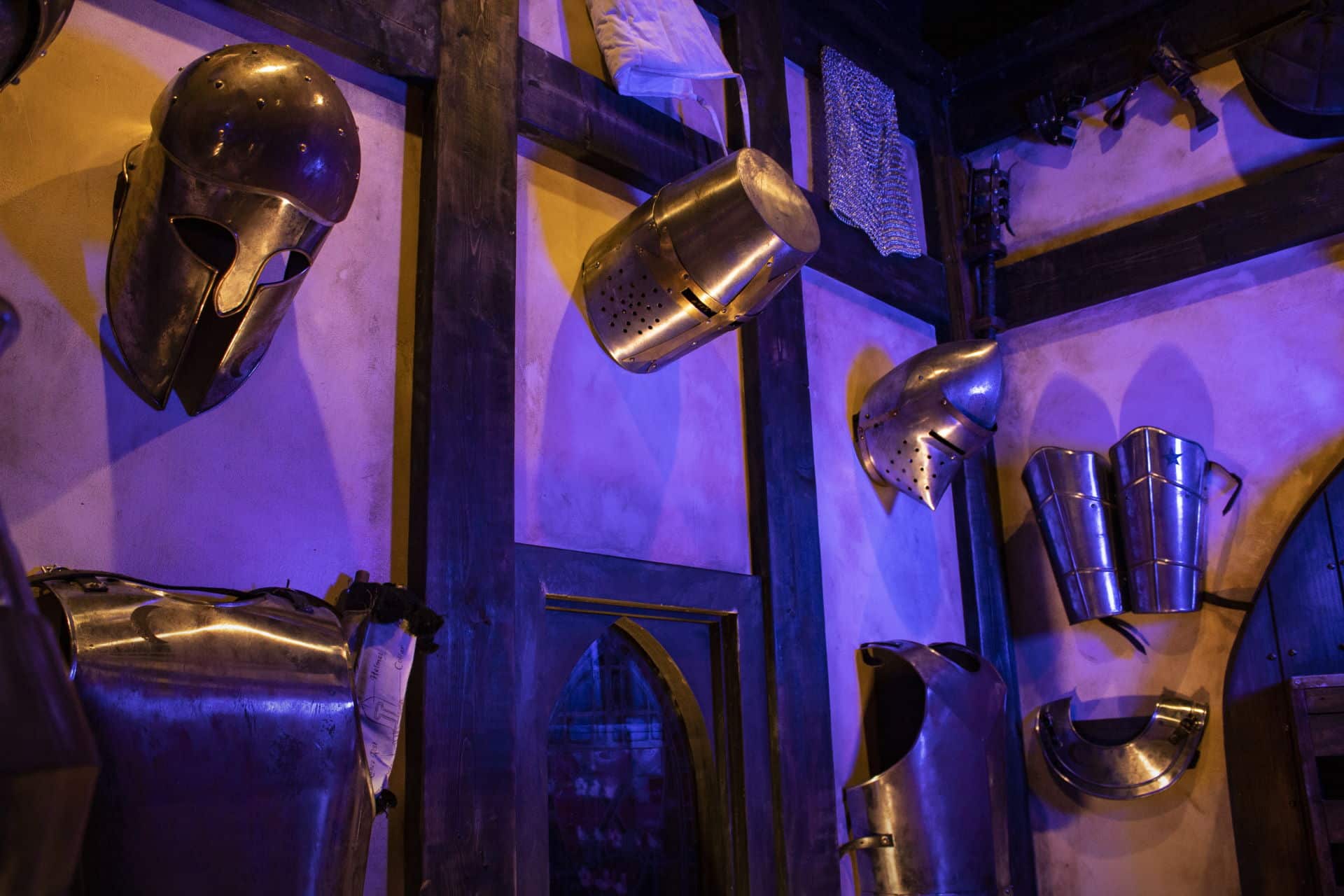 Various pieces of armor hang on the armory walls and are illuminated by a faint blue light.