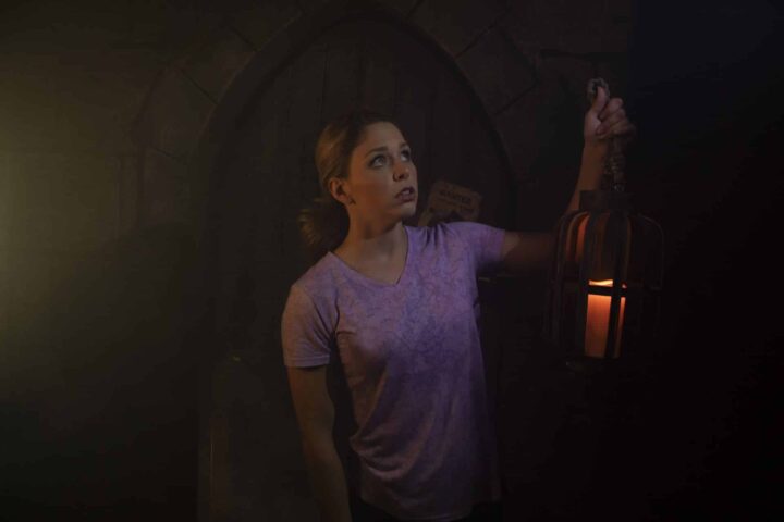 A frightened player explores the dark courtyard with her lantern.