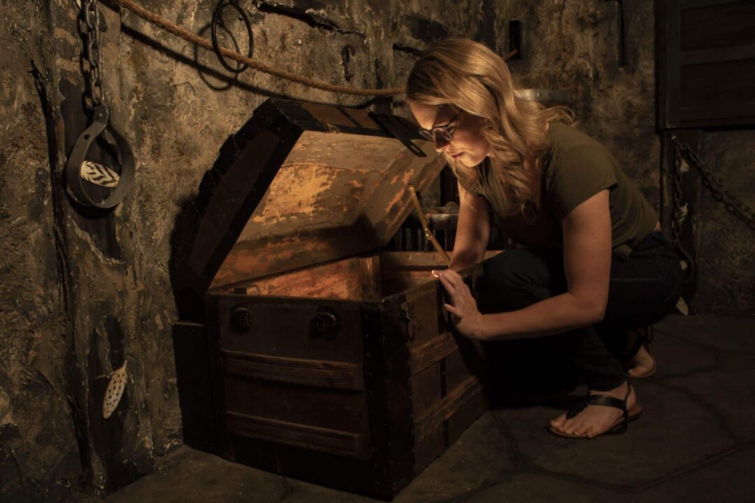 An escape room is a great place for a date night! Thos player is reaching into a glowing treasure chest.