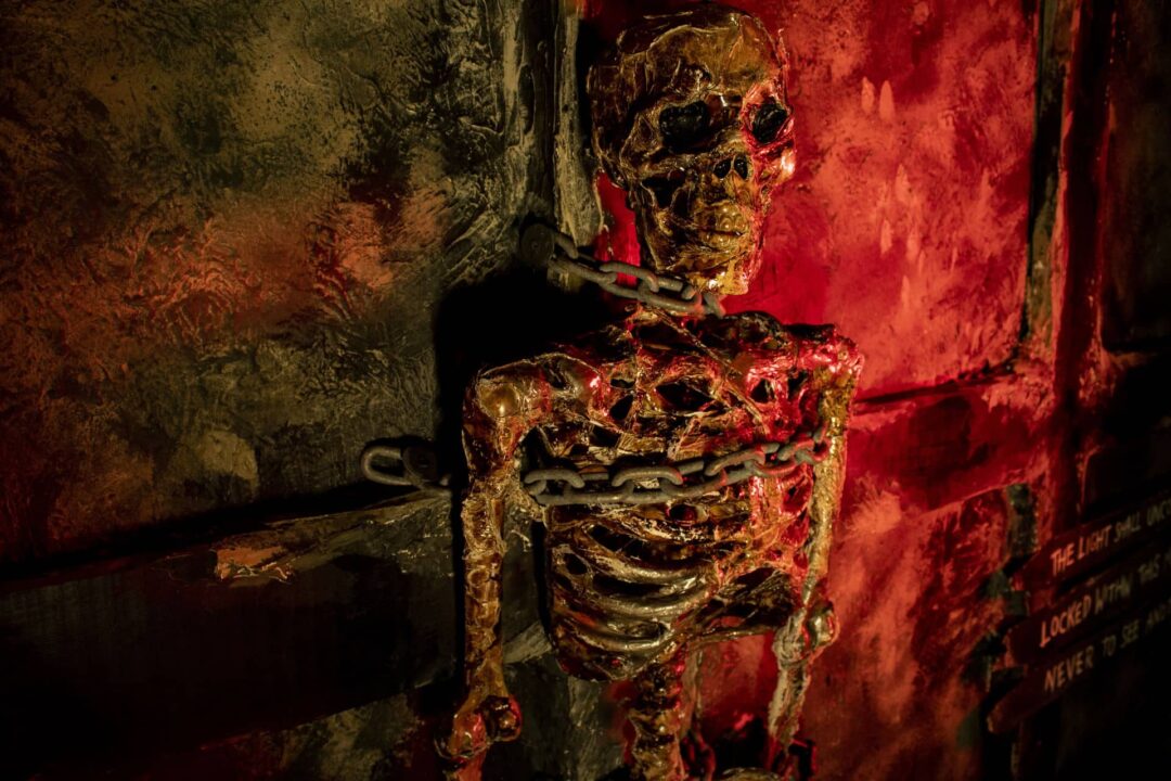 A desiccated skeleton of a prisoner is chained to the wall of the dungeon cell.