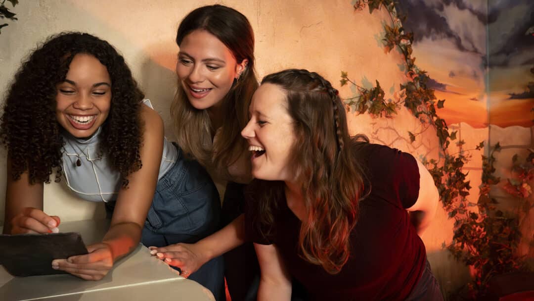 Three players laugh as they solve a puzzle.
