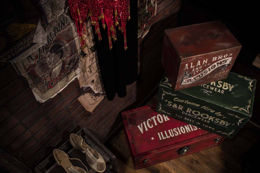 A photograph showing inside the dressing room, showing shoes, magician storage chests and dresses.
