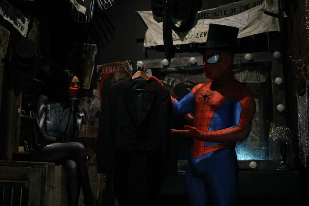 Spiderman wears a top hat and shows Silk his tuxedo.