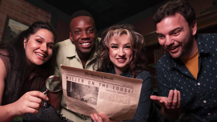 Four friends smile as they study a newspaper that holds a secret.