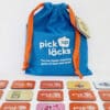 A bag of Pick Up Locks with tiles arranged in a grid in front of it.